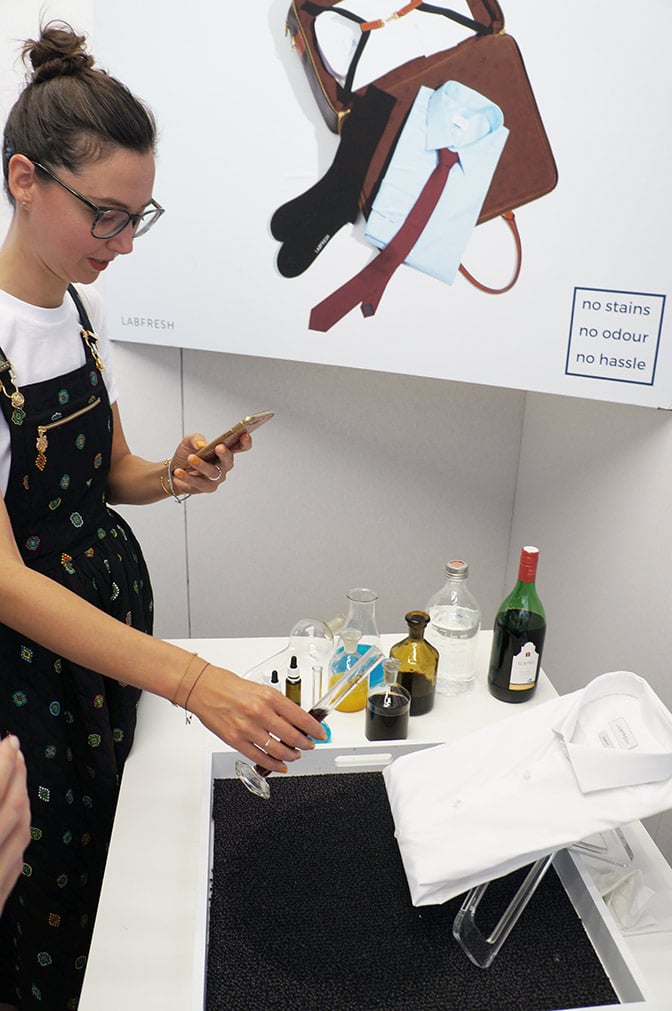 A girl is pouring wine on a white shirt as a part of the Labfresh exhibit at the The Future Generation exhibition at the Mercedes-Benz Amsterdam Fashion Week July 2017